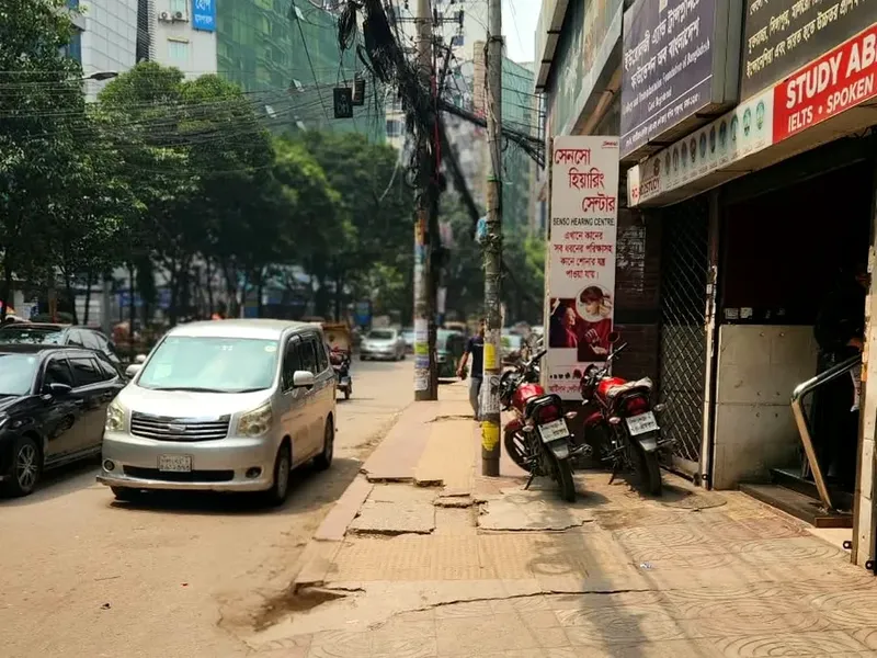 ফুটপাতে দাঁড়ানো মোটরসাইকেলের পাশে সেনসো হিয়ারিং সেন্টারের সাদা-লাল বোর্ড ও ভবনের প্রবেশমুখ